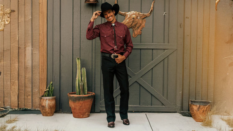 A man wearing a pair of Signature Series boots, standing in front of a green barn.